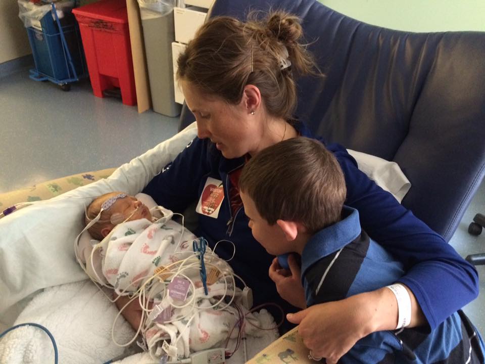 Dr. Sarah Diamond holding her younger son while standing beside her older son, family portrait.